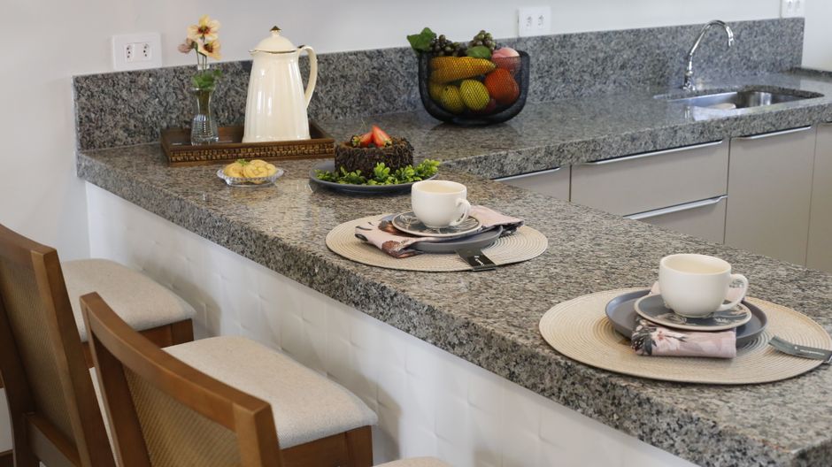 Kitchen counter with a stone top and cups set out.