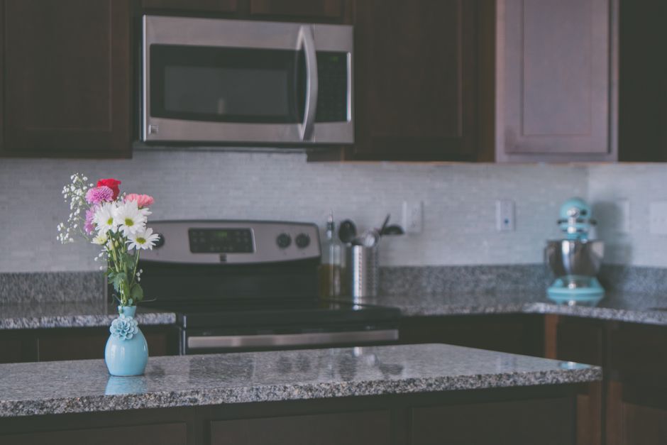 A contemporary kitchen featuring granite countertops and a vase of flowers.